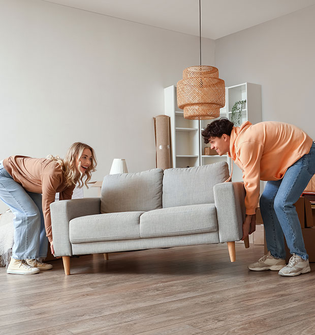 Young couple carrying a couch as they move into their new home.